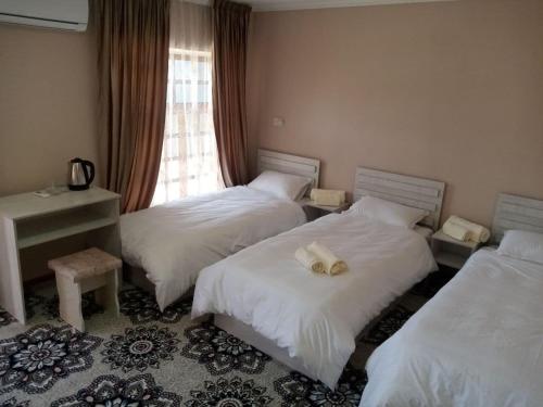 una camera d'albergo con due letti e una finestra di Istirohat guest house a Samarkand
