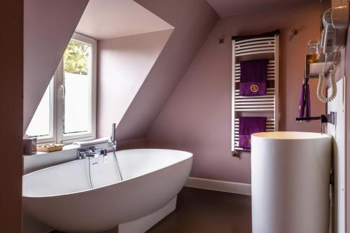 Saint Georges Bruges Luxury Suites في بروج: حمام مع حوض أبيض كبير ونافذة