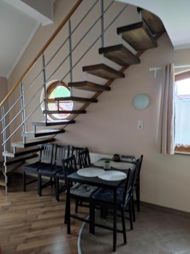uma sala de jantar com uma mesa e cadeiras e uma escadaria em Tiborc Apartman em Gyula
