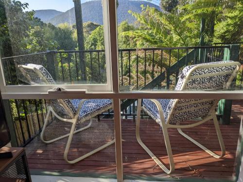 two chairs on a balcony with a view of the mountains at Littlehurst Lodge in Millgrove