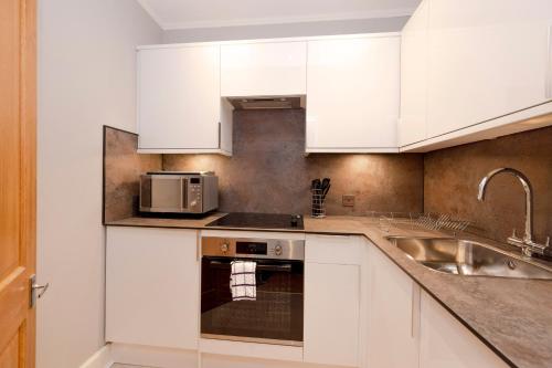 een keuken met witte kasten en een wastafel bij JOIVY Attractive flat near Haymarket Station in Edinburgh
