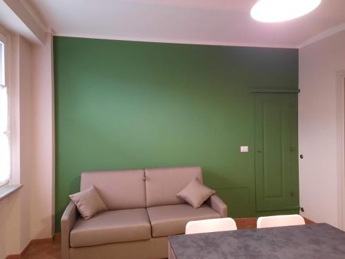 sala de estar con sofá y pared verde en Cà Trifolera Barbaresco - Appartamento per 2 o 4 persone immerso nei vigneti - Free Parking Wi-Fi -, en Barbaresco