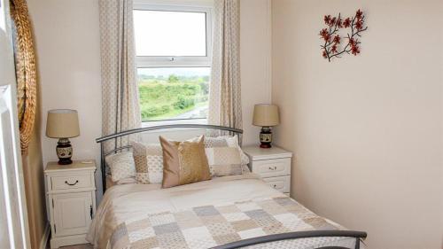 een slaapkamer met een bed met 2 nachtkastjes en een raam bij Spacious Holiday Home in Cumbria in Arlecdon