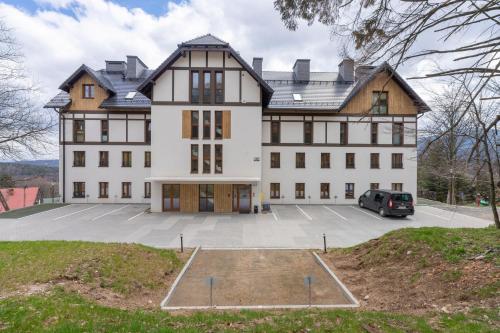 a large house with a car parked in a parking lot at RentPlanet - Green Park Resort in Szklarska Poręba