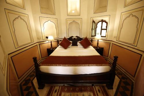 a bedroom with a bed with two pillows on it at Hotel Narain Niwas Palace in Jaipur