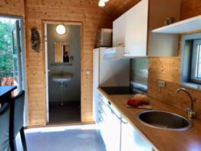 a small kitchen with a sink and a refrigerator at Tranum Klit Camping og Hytteudlejning in Brovst
