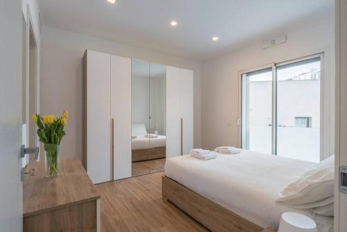 um quarto branco com uma cama e um vaso de flores em NEW! Exclusive Eur Apartment em Roma