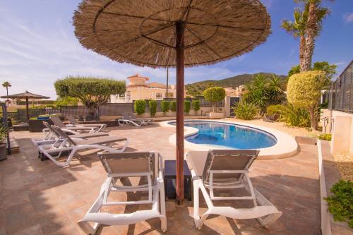a patio with chairs and an umbrella and a pool at Villa moderna con piscina in El Campello