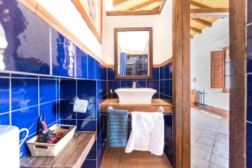 baño con paredes de azulejos azules y lavabo en Cortijo Las Caballerias en Alora