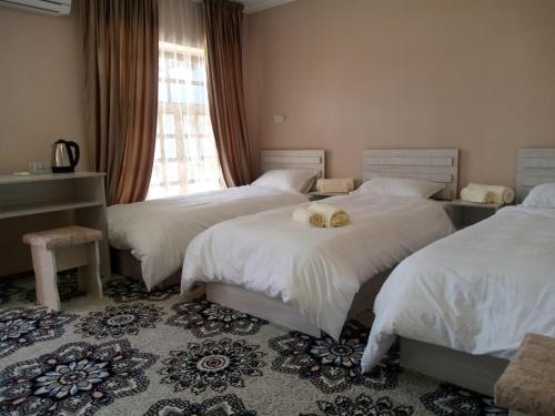 a bedroom with two beds with white sheets and a window at Istirohat guest house in Samarkand