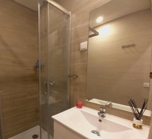 a bathroom with a glass shower and a sink at Casa Vila Praia in Sesimbra