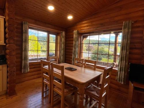 comedor con mesa, sillas y ventanas en Solid Log Cabin With Private Hot Tub - Oak, en Aymestrey