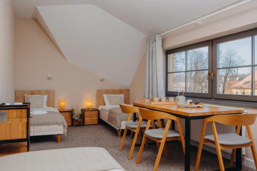 een kamer met een tafel en stoelen, een bed en een raam bij Pokoje Bukowiec Folwark i Park in Bukowiec