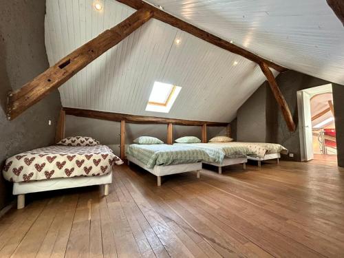2 Betten in einem Dachzimmer mit Holzböden in der Unterkunft Le domaine de Jade in Châtillon-la-Borde