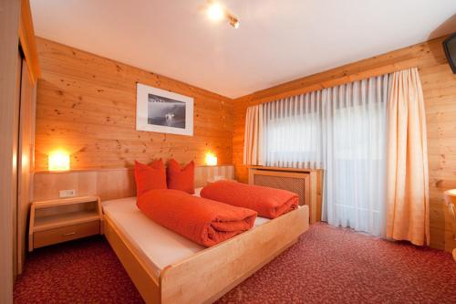 ノイシュティフト・イム・シュトゥーバイタールにあるPension Kristallのベッドルーム1室(オレンジ色の枕が付いたベッド1台付)
