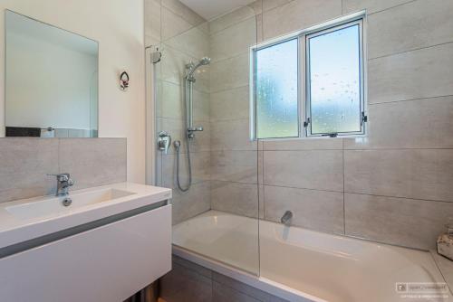 a bathroom with a tub and a sink and a shower at Tui's Song Bach on the Bay in Whangarei