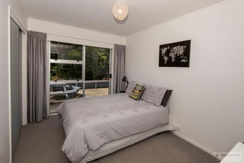 a bedroom with a bed and a large window at Tui's Song Bach on the Bay in Whangarei