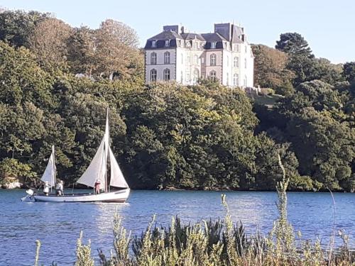 ein Segelboot auf dem Wasser vor einem Schloss in der Unterkunft Un appartement au château de Locquéran Finistère in Plouhinec