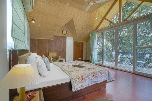 a bedroom with a bed and a large window at SaffronStays Woodpeckers Perch Villa, Dehradun in Rājpur
