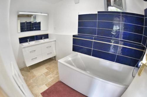 ein blau-weißes Bad mit einer Badewanne und einem Waschbecken in der Unterkunft Maison chaleureuse au cœur du perche sarthois in Bessé-sur-Braye