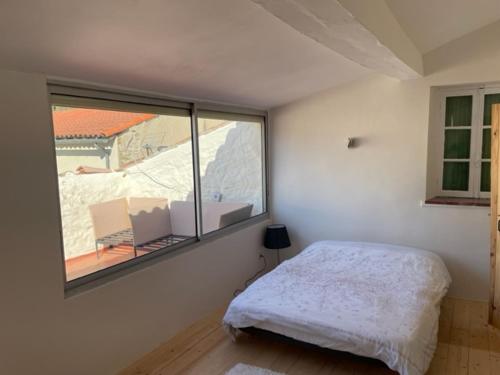 een slaapkamer met een bed en een groot raam bij Maison confortable in Espéraza