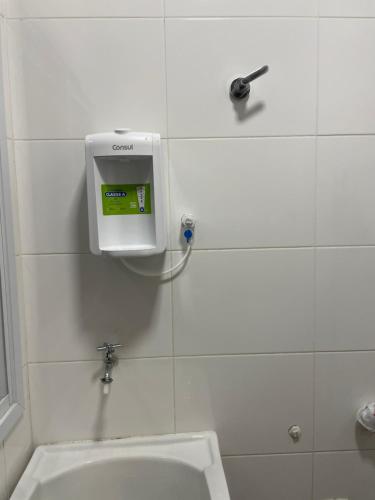 a bathroom with a sink and a soap dispenser on the wall at Apartamento Praia do Morro in Guarapari