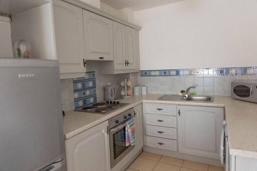 a white kitchen with white cabinets and a sink at City Centre Riverview Apartment in Derry Londonderry
