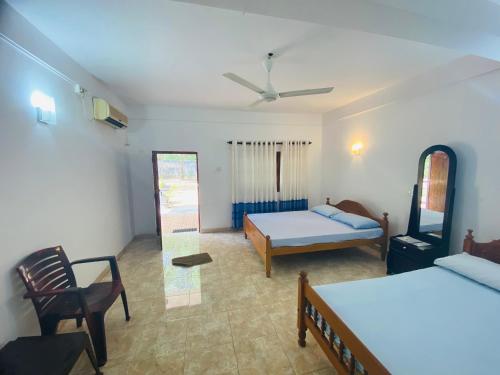 a bedroom with two beds and a couch and a chair at Emerald Guest House in Kataragama