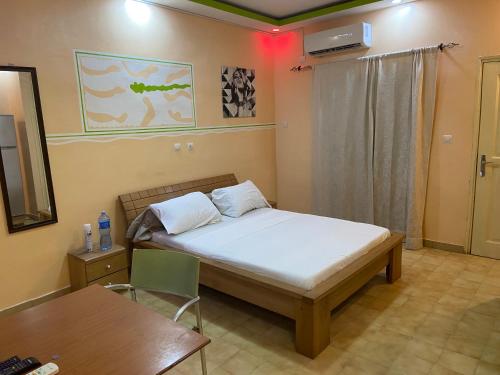 een slaapkamer met een bed, een bureau en een tafel bij Résidence Comara in Marcory