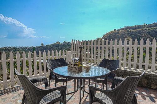 a table and chairs on a patio with a fence at SaffronStays Woodpeckers Perch Villa, Dehradun in Rājpur