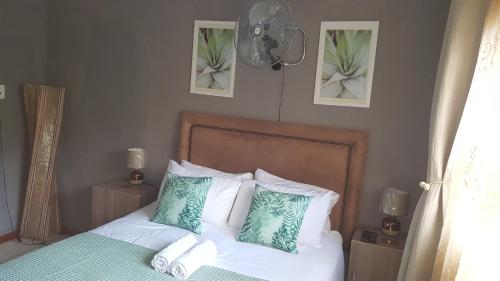 um quarto com uma cama com almofadas verdes e brancas em Kadichueni Guest House em Zeerust