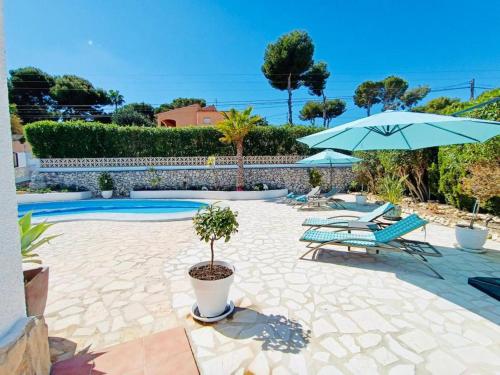 a patio with chairs and an umbrella and a pool at 1-Bed Apartment close to Moraira town centre in Moraira