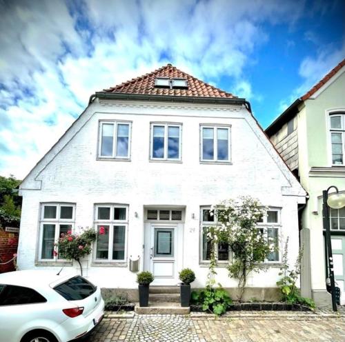 uma casa branca com um carro estacionado na frente em Fischerhuus em Eckernförde