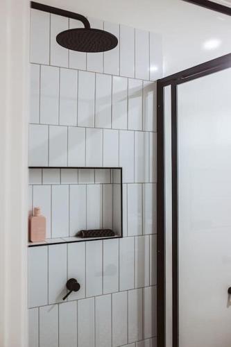 a white tiled wall with a shelf in a bathroom at An Unexpected Delight in the Heart of Town in Bendigo
