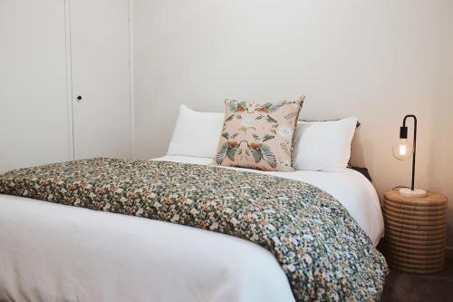 um quarto com uma cama branca e um cobertor floral em An Unexpected Delight in the Heart of Town em Bendigo