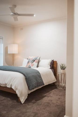 a white bedroom with a bed and a ceiling fan at An Unexpected Delight in the Heart of Town in Bendigo