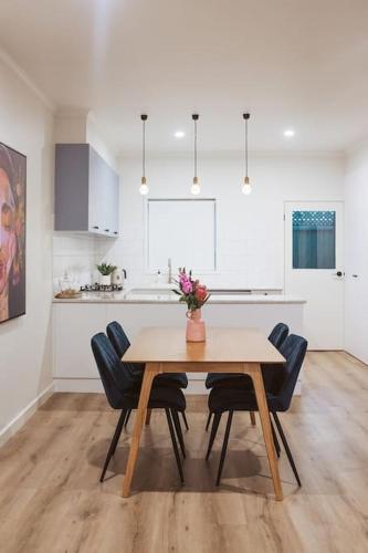 a dining room table with chairs and a kitchen at An Unexpected Delight in the Heart of Town in Bendigo