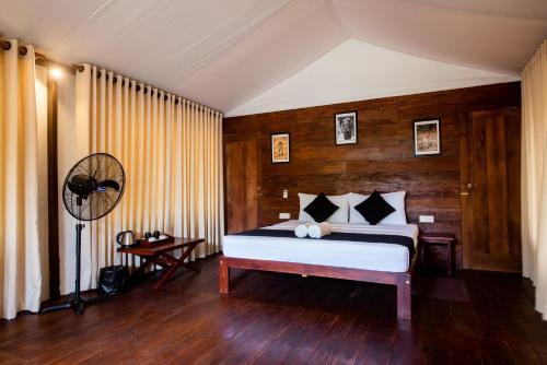 a bedroom with a bed and a wooden wall at Wild Trails Yala by Suri in Yala