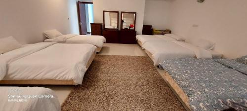 a room with four beds in a room with a mirror at Family friendly house in Bahrian in Durrat Al Bahrain