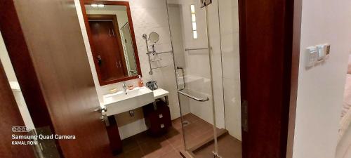 a bathroom with a sink and a shower with a mirror at Family friendly house in Bahrian in Durrat Al Bahrain