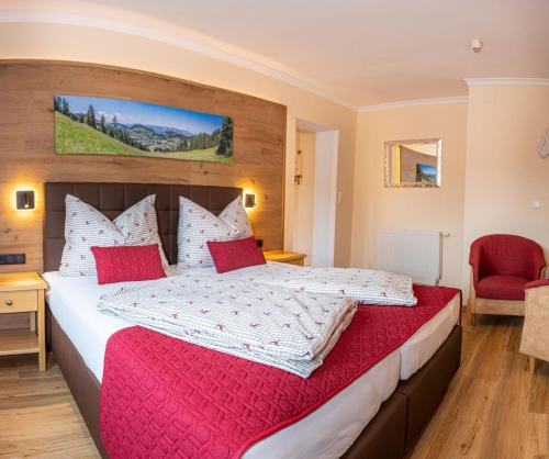a bedroom with a large bed with red pillows at Hotel Schneeberger in Niederau