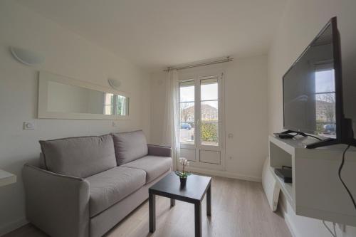 a living room with a couch and a flat screen tv at Studio Cosy 2 min Gare - 10 min in Bussy-Saint-Georges