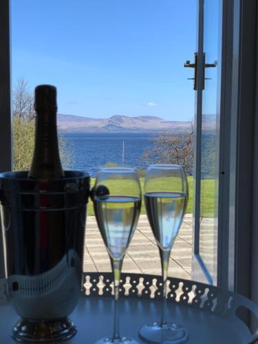 two wine glasses sitting on a table with a bottle of wine at Lomond View in Luss