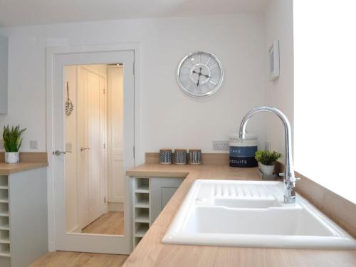 a kitchen with a sink and a clock on the wall at Keyland Cottage in Johnshaven