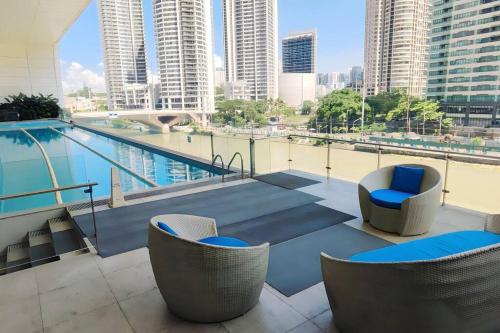 a balcony with chairs and a swimming pool on a building at Aveline Suites Cozy Skyline View ACQUA Private Residences near Rockwell Makati in Manila