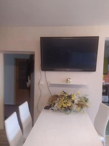 mesa blanca con sillas y TV en la pared en Dům u zanety, en Jundrov