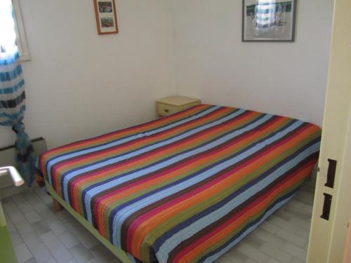 łóżko z kolorowym paskiem w pokoju w obiekcie 5097 Tennis Village 1603 w Cap d'Agde