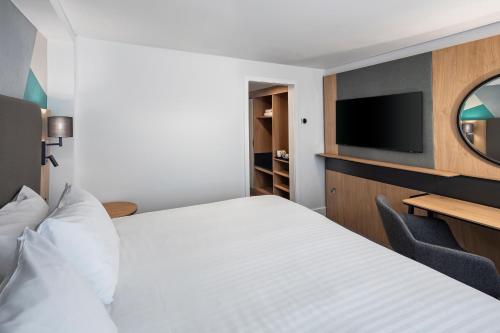 a hotel room with a bed and a flat screen tv at Holiday Inn London-Bexley by IHG in Bexley