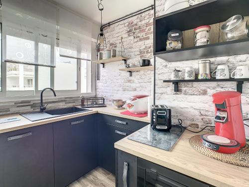 une cuisine avec des armoires bleues et un appareil rouge sur un comptoir dans l'établissement La Bulle, à Royan