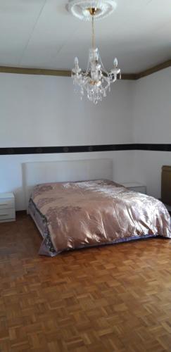 un letto in una camera con soffitto e lampadario a braccio di Alloggio in paese a Montà